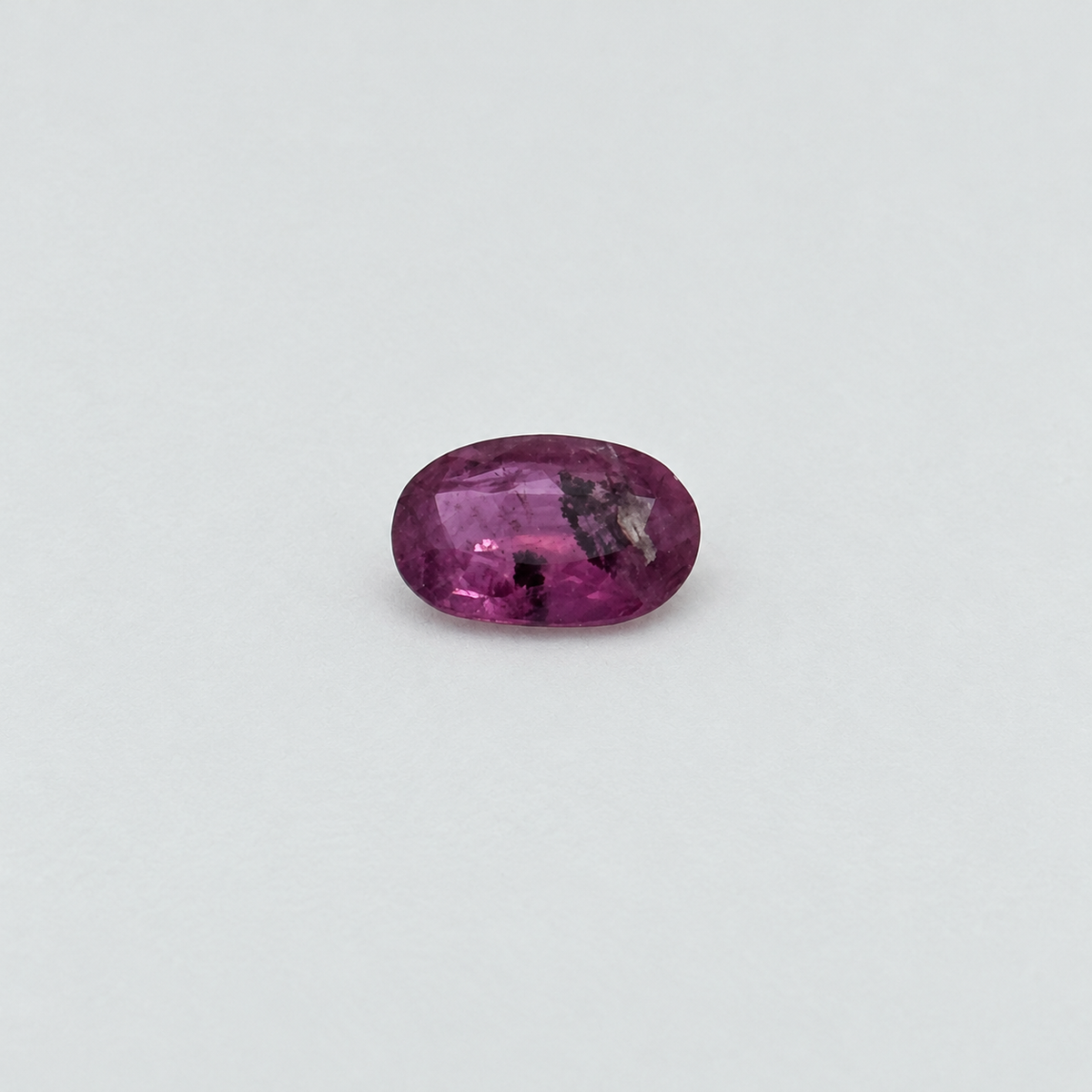 148 Ruby 0.65 ct, oval pink-purple gemstone with visible inclusions